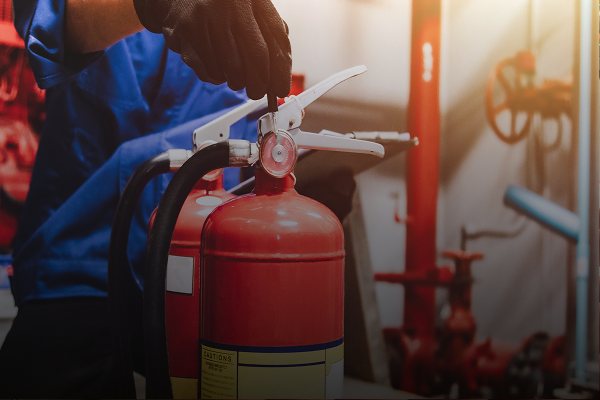 Extintor de incêndio vermelho sendo inspecionado em ambiente industrial